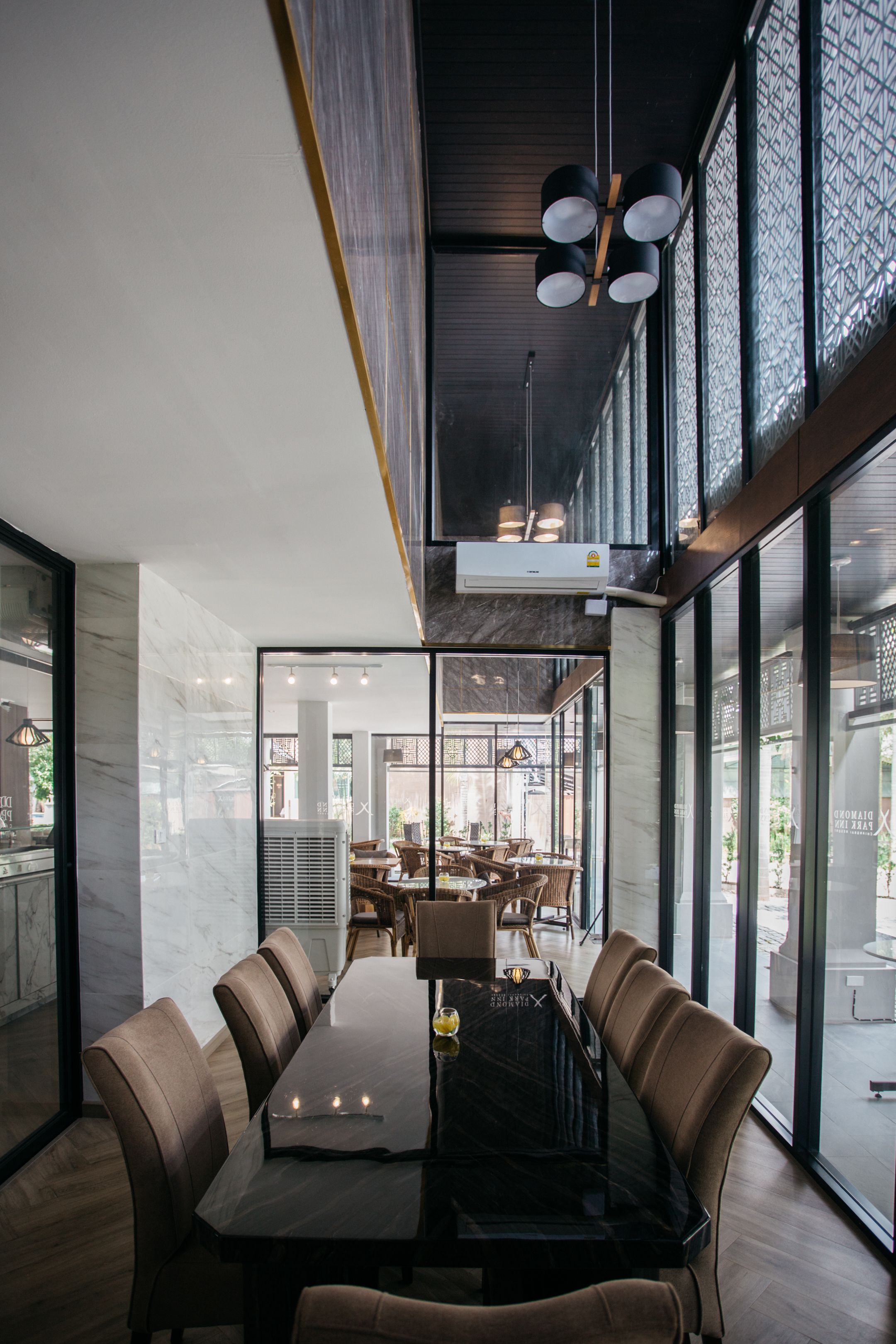 Un espace de restauration moderne, doté d’une longue table, de sièges confortables et de grandes fenêtres offrant une vue sur l’extérieur.