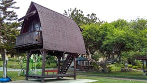 A small wooden structure with a sloped roof and a balcony, surrounded by greenery and trees. - Amazing Beach Resort - Palu (Palu)