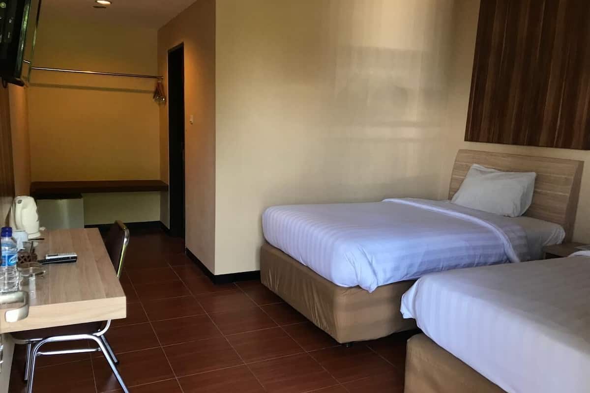 A hotel room with two beds, a wooden table, and a chair.