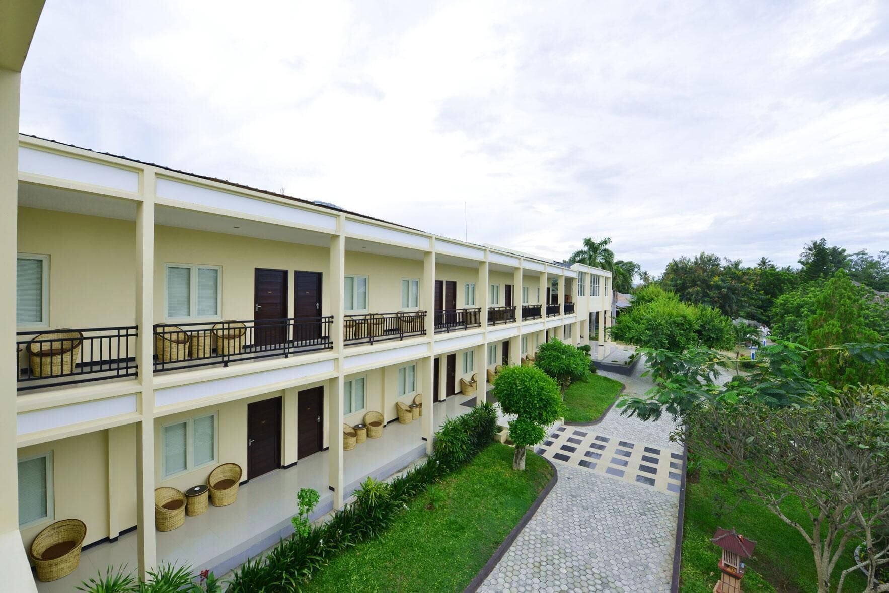 A multi-story hotel with balconies, outdoor seating, and a garden area.