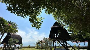 A beachside resort with thatched-roof structures, a clear view of the sea, and a well-maintained garden area. - Amazing Beach Resort - Palu (Palu)