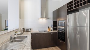 A modern kitchen with dark cabinetry, stainless steel appliances, and a granite countertop. - Club Wyndham Perth, Trademark Collection by Wyndham (West Perth)