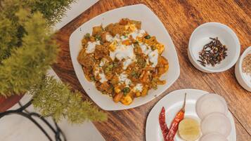 Un plato de comida con un cuenco blanco de especias y una fuente de cebolla en rodajas, además de un chile rojo.