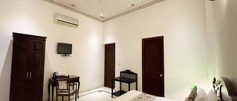 A hotel room with a bed, a desk, a chair, a television, and a wardrobe.