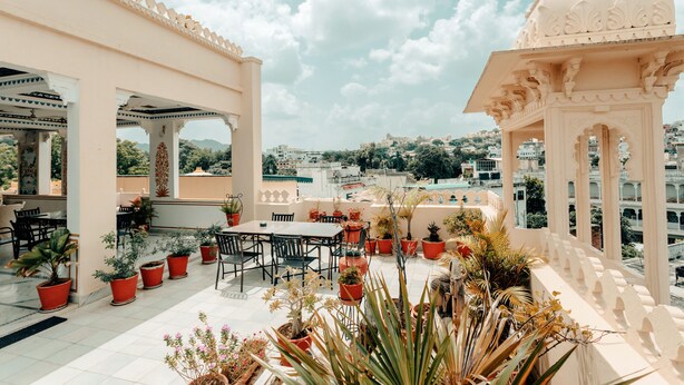 Terraza en la azotea con zona de comedor, plantas en macetas y vistas a la ciudad.