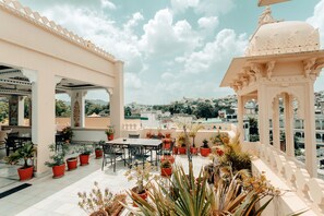 Una terrazza sul tetto con zona pranzo, piante in vaso e vista sulla città.