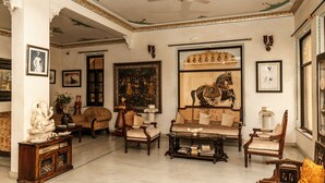 Un salón amplio con muebles tradicionales, ventilador de techo y obras de arte en las paredes.