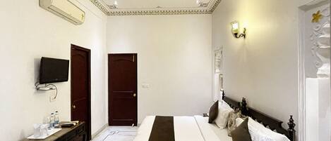 Una habitación de hotel con cama, escritorio, televisor y puerta.