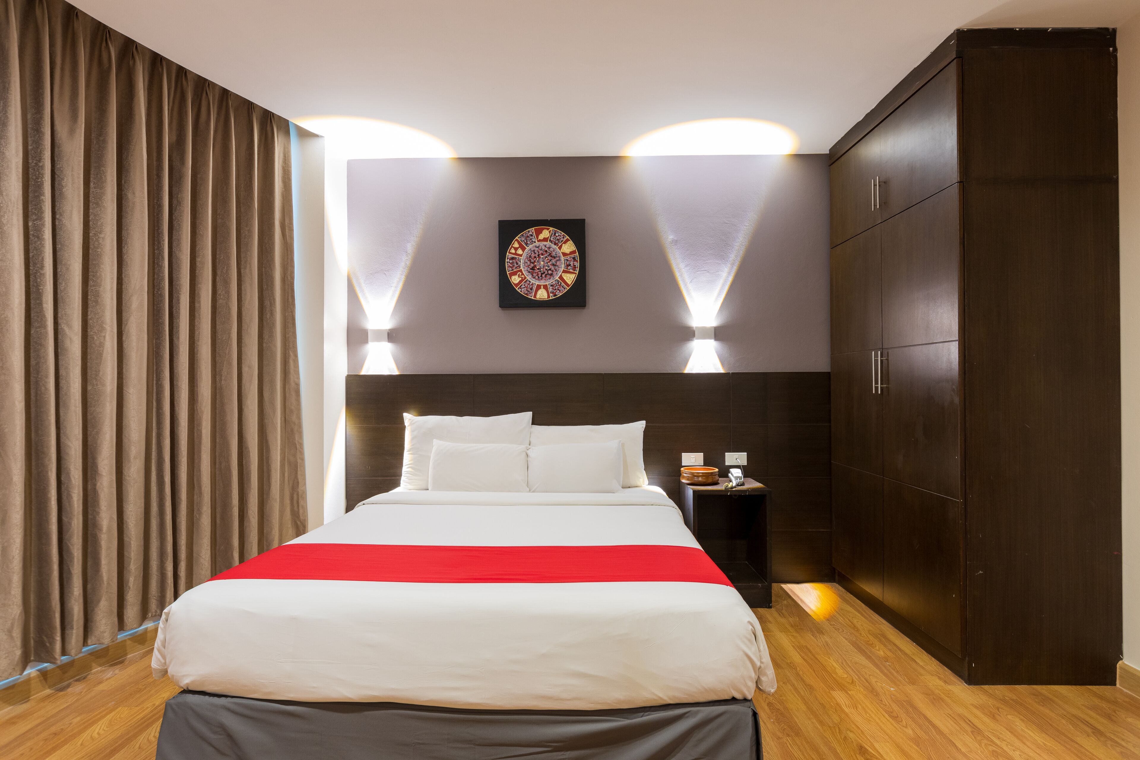 Una camera d'albergo moderna con un letto grande, un comodino, un armadio e un'opera d'arte appesa al muro.