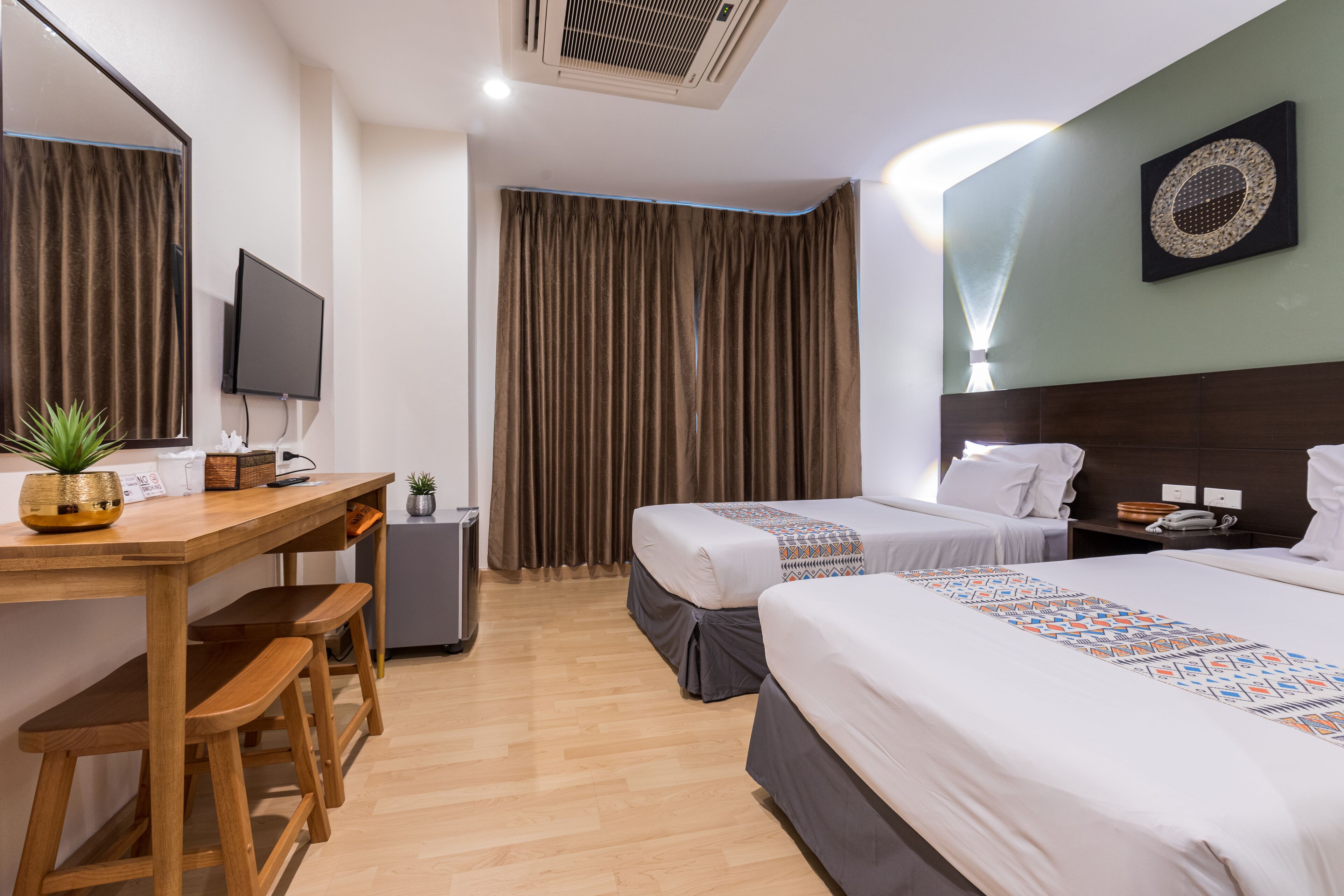 A hotel room with two beds, a desk with a chair, a TV, and a large window with curtains.