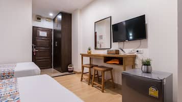 Une chambre d’hôtel avec deux lits, un bureau avec une chaise, une télévision, un petit réfrigérateur et une porte en bois.