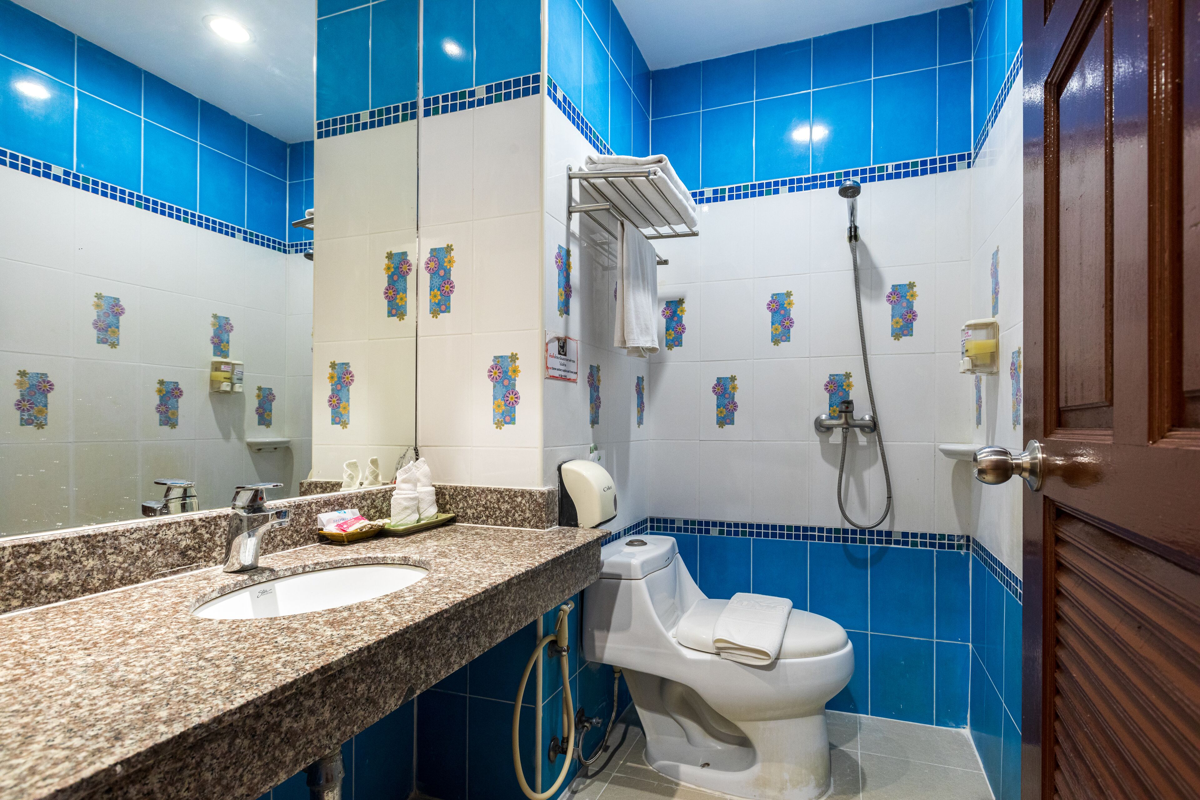 A bathroom with a granite countertop sink, a white toilet, and a shower.