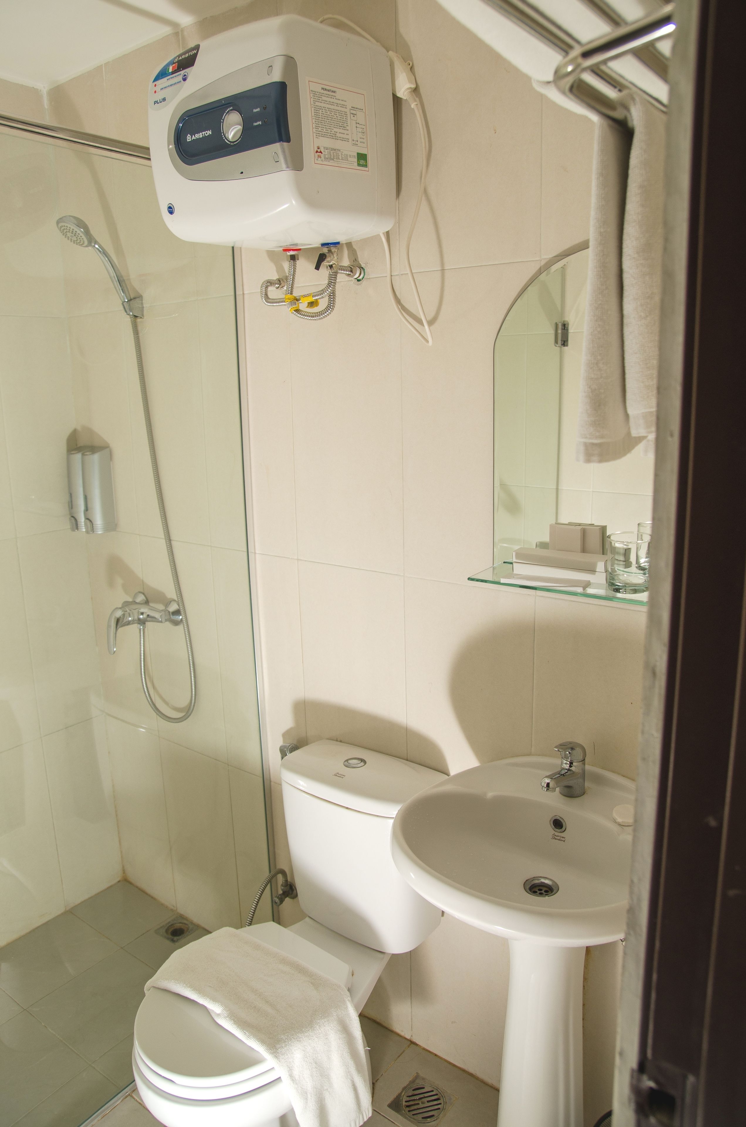 A bathroom with a glass shower enclosure, a toilet, a sink, and a mirror.