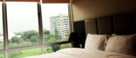 A hotel room with a large window, a bed, and a nightstand.