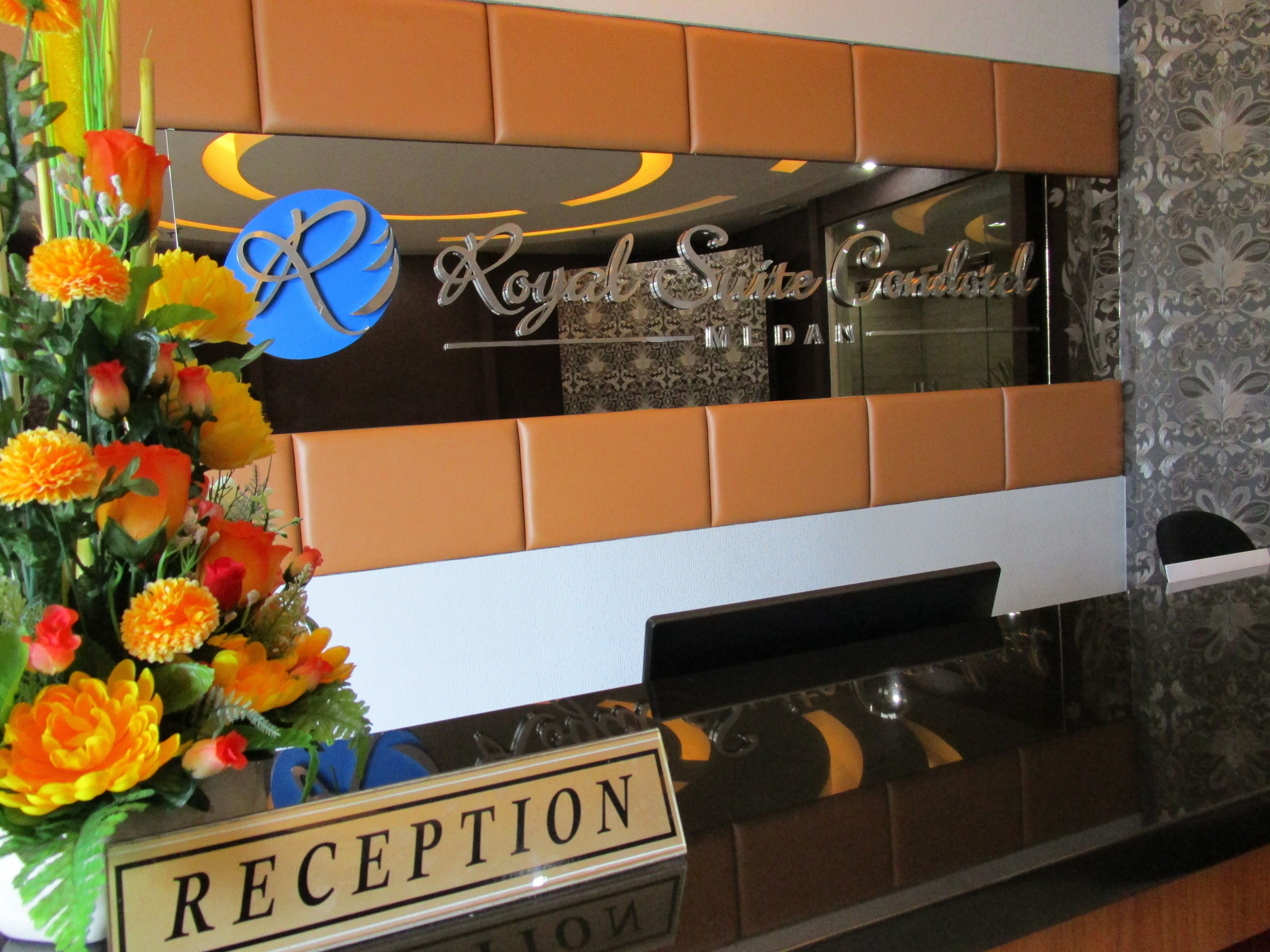 Un mostrador de recepción con un cartel que dice "RECEPTION" y un arreglo floral decorativo.
