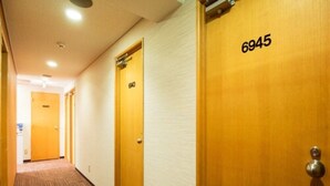 Ein Hotelkorridor mit Teppichböden, Holztüren und einer Decke mit eingelassenen Leuchten.