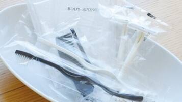 A white plate with various personal care items like toothbrushes and body sponges, all in clear plastic packaging.