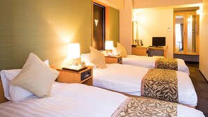 Ein Hotelzimmer mit zwei Betten, jeweils mit Kissen und einem Nachttisch mit Lampe. An der Wand befindet sich ein Spiegel und ein Fernseher auf einem Schrank.