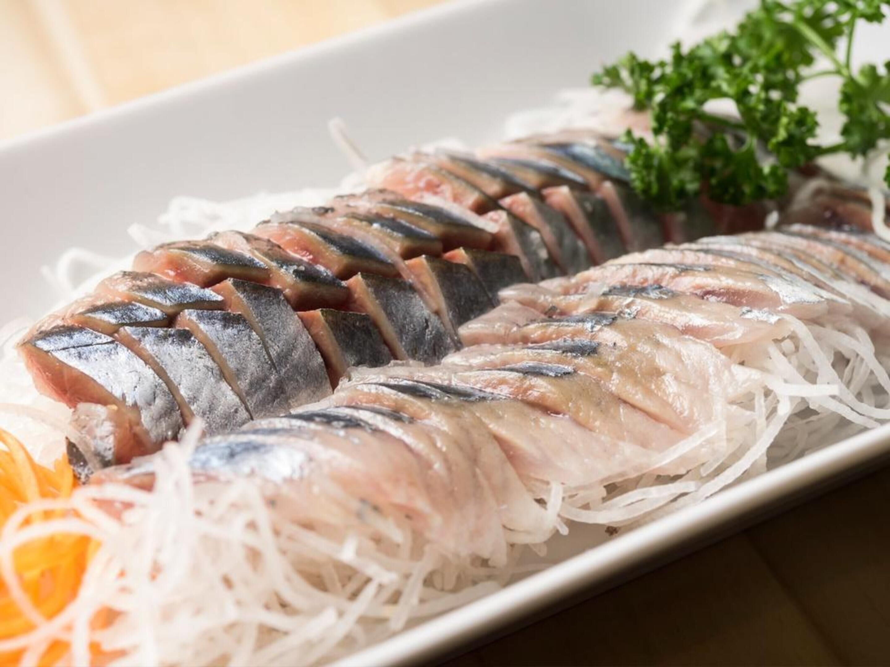En tallerken med sashimi, fisk, strimlet grøntsager og pynt.