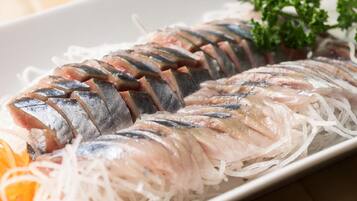 Eine Platte mit Sashimi, Fisch, gehobelten Gemüsesorten und einer Dekoration.