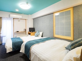 A hotel room with two beds, a TV, a desk, and a large window.