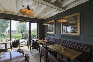 A restaurant with wooden tables and benches, large windows, and hanging pendant lights. - Im-Jaich Wasserferienwelt (Putbus)