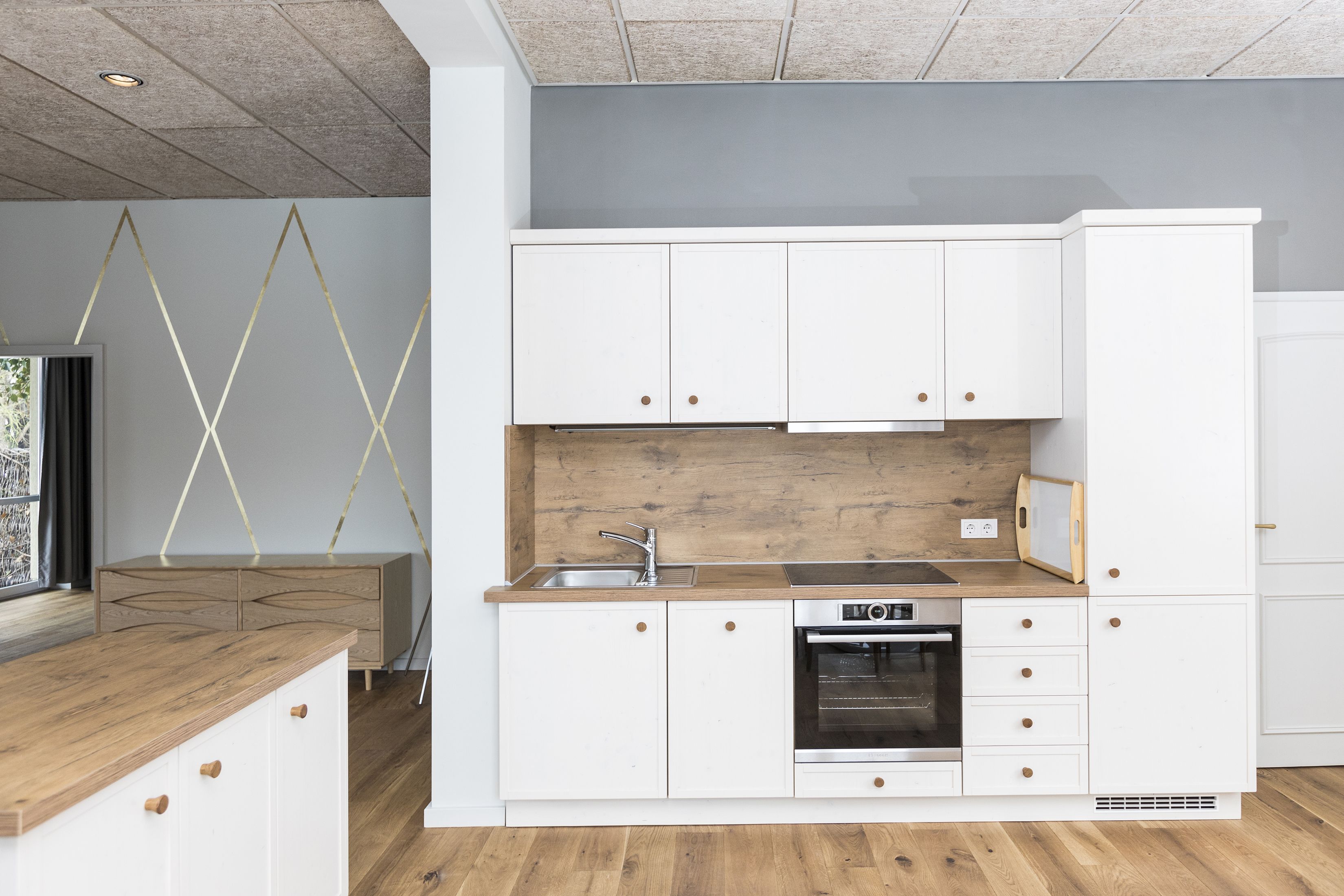 A modern kitchen with white cabinetry, a wooden countertop, and a built-in oven.