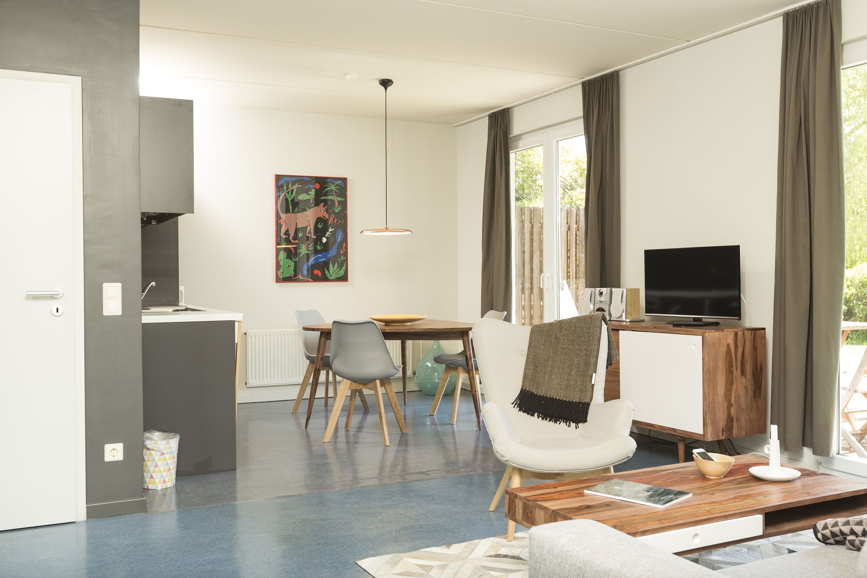 A modern living room with a dining area, a TV, and a painting on the wall.