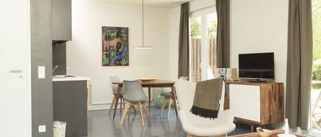 A modern living room with a dining area, a TV, and a painting on the wall.
