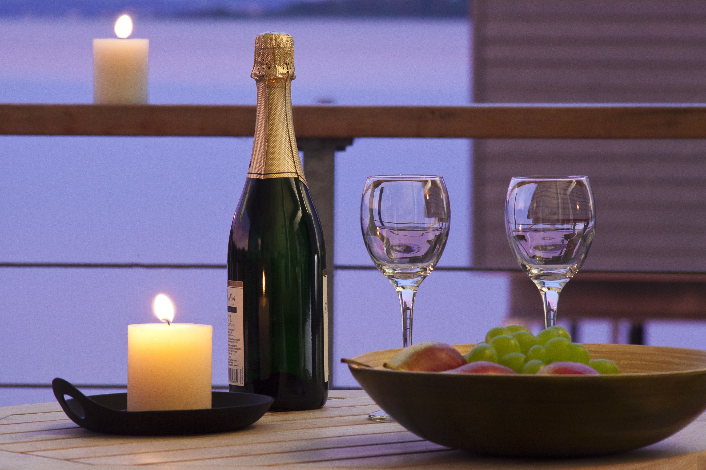 Ein Tisch mit einer Champagnerflasche, zwei Gläsern, einer Kerze und einer Obstschale.