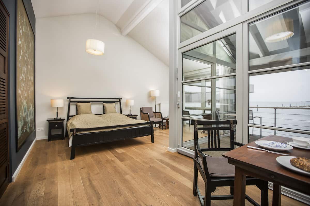 A bedroom with a large bed, bedside tables, a chair, and a table with plates.