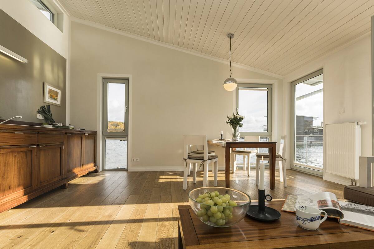 A spacious kitchen with wooden cabinets, a dining area with a table and chairs, and a view of the water outside.