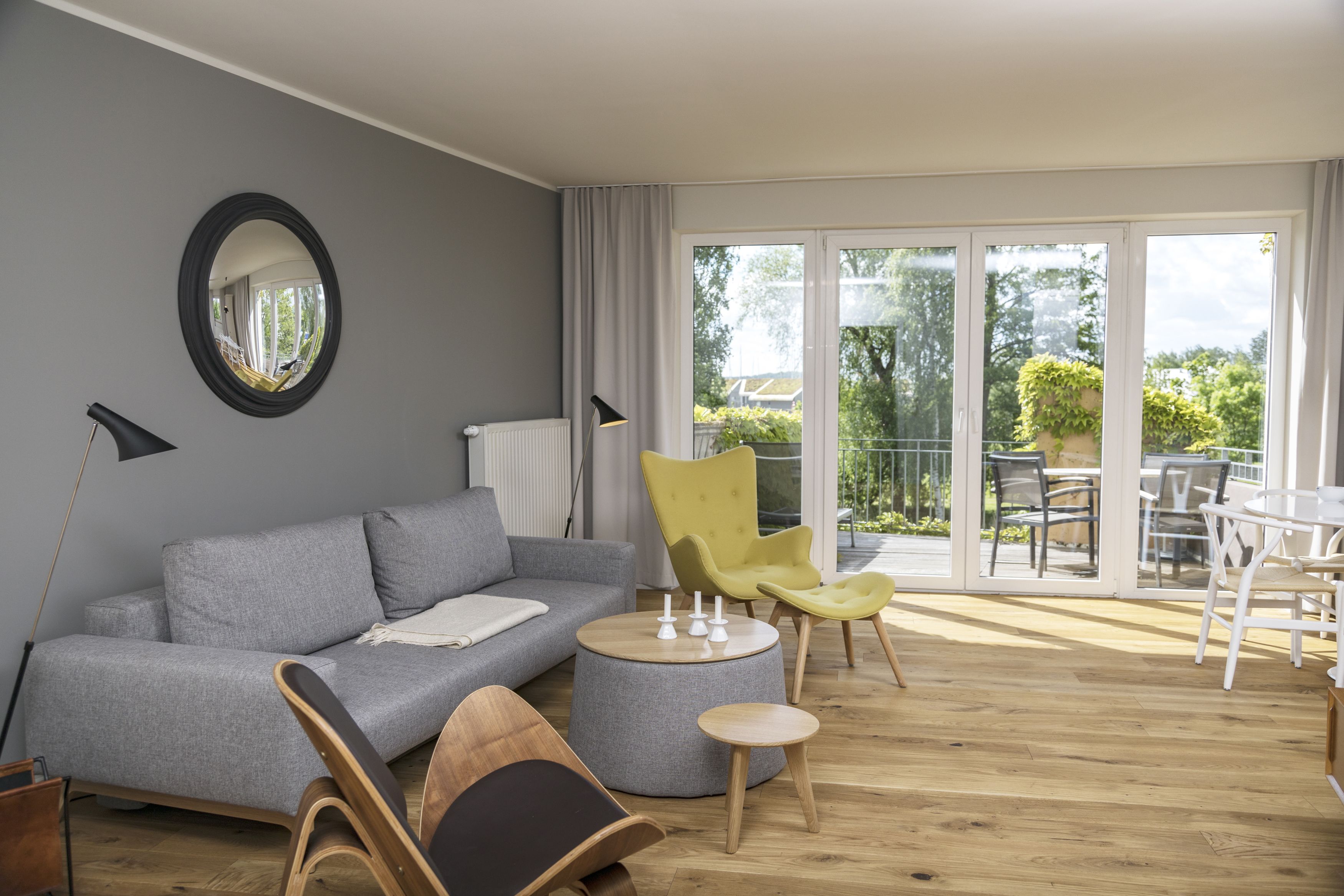 Una sala moderna con un sofá gris, un sillón amarillo y una mesa de centro redonda.