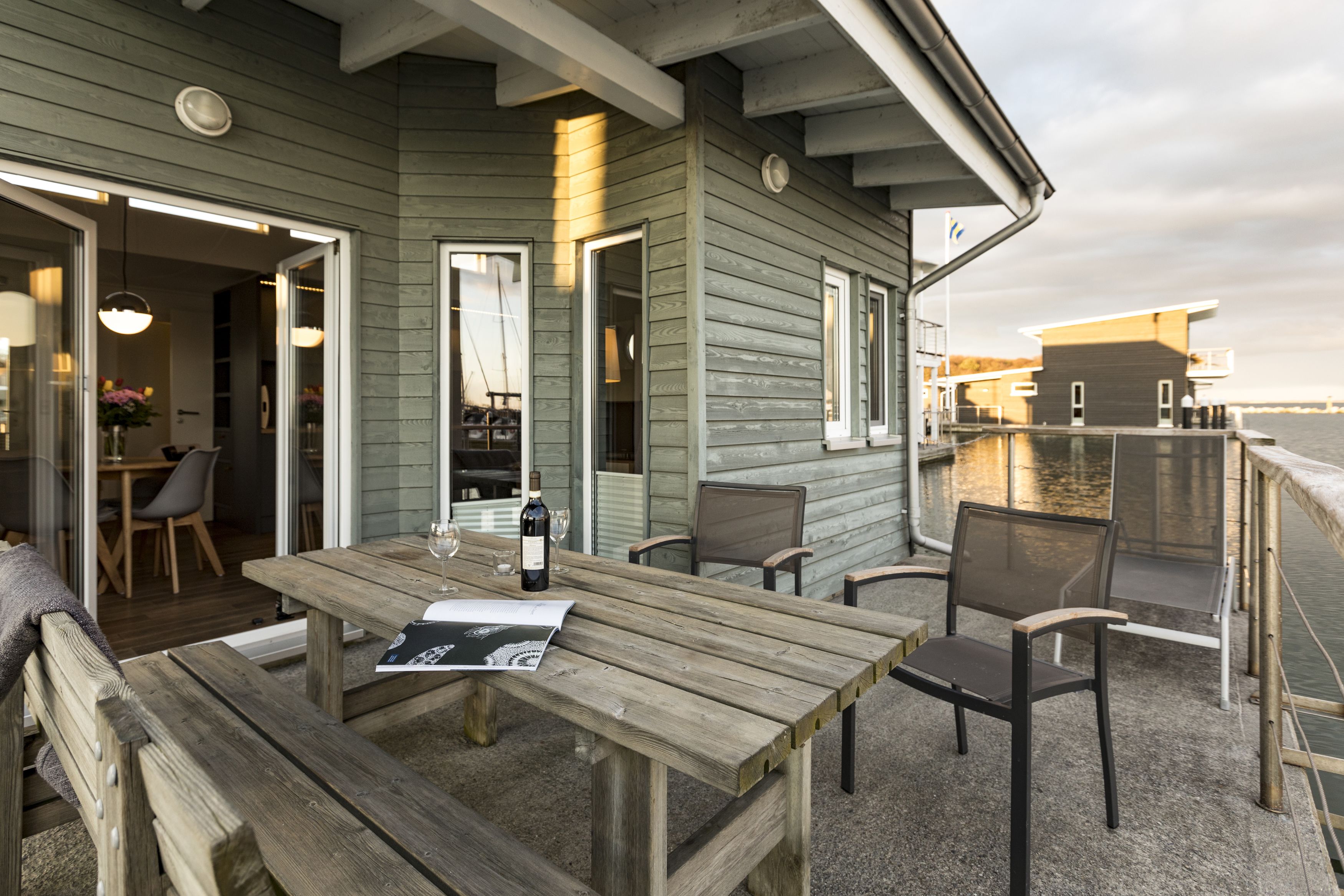 A wooden deck with a table and chairs, overlooking a body of water.