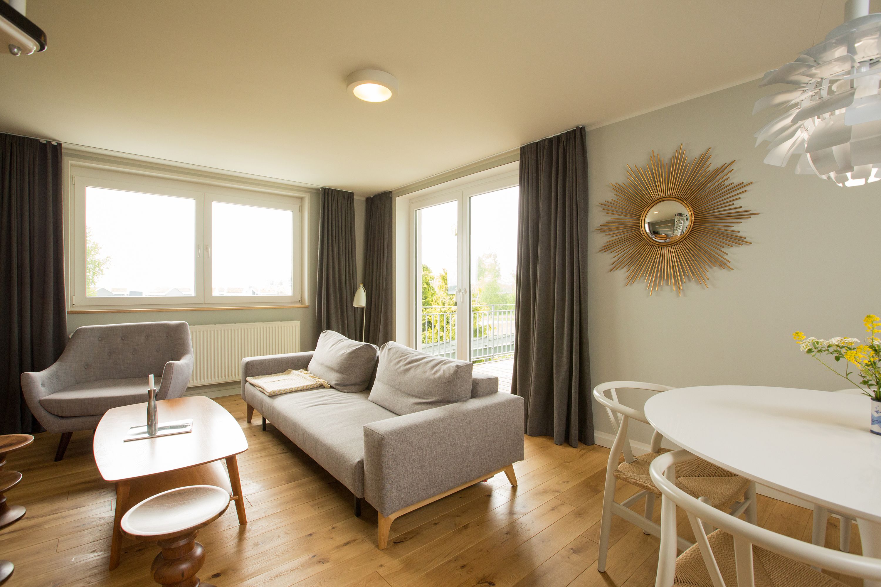 A modern living room with a sofa, a small table, and a dining table.