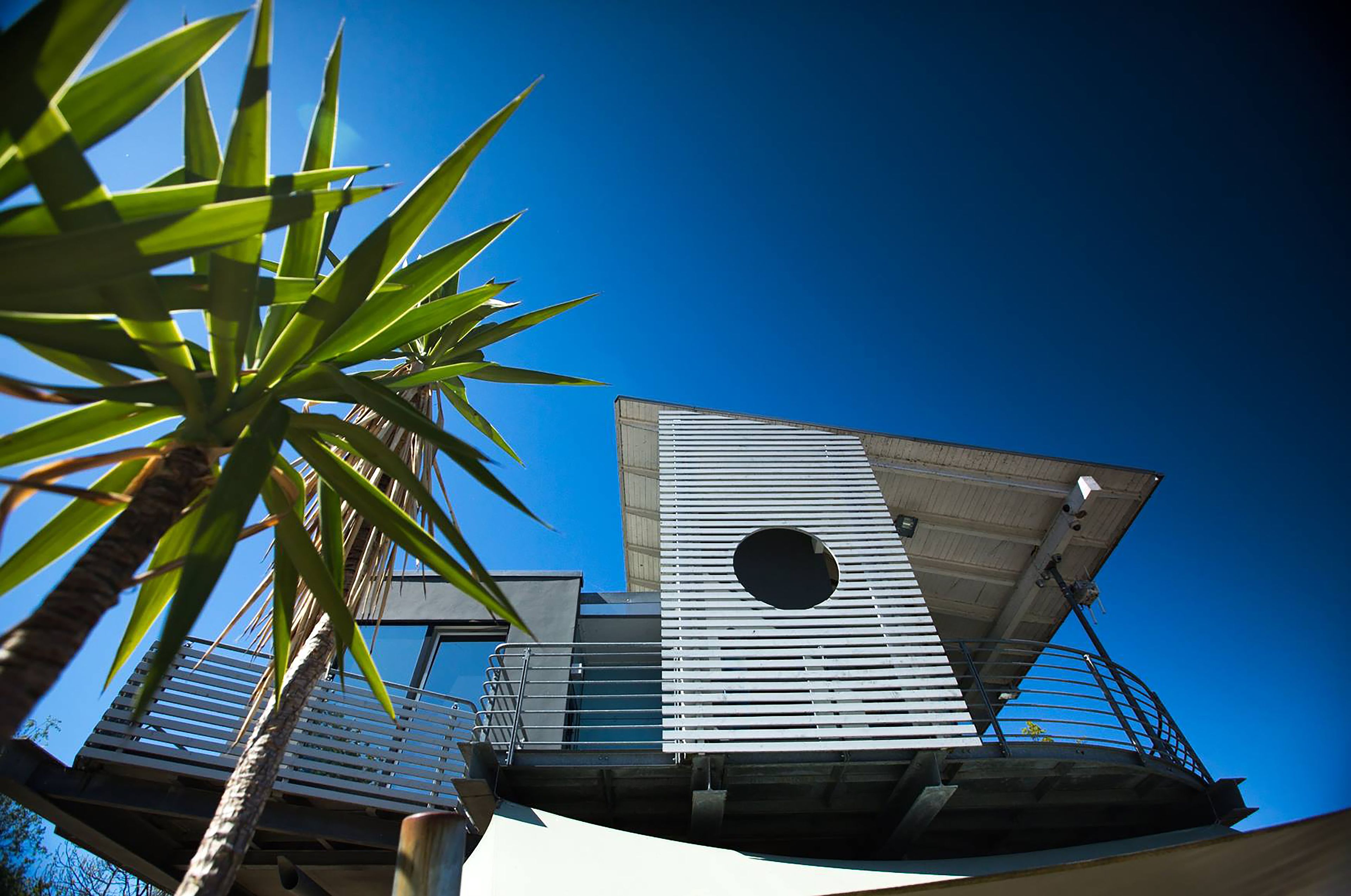 A modern building with a sloped roof, a circular window, and a metal railing.