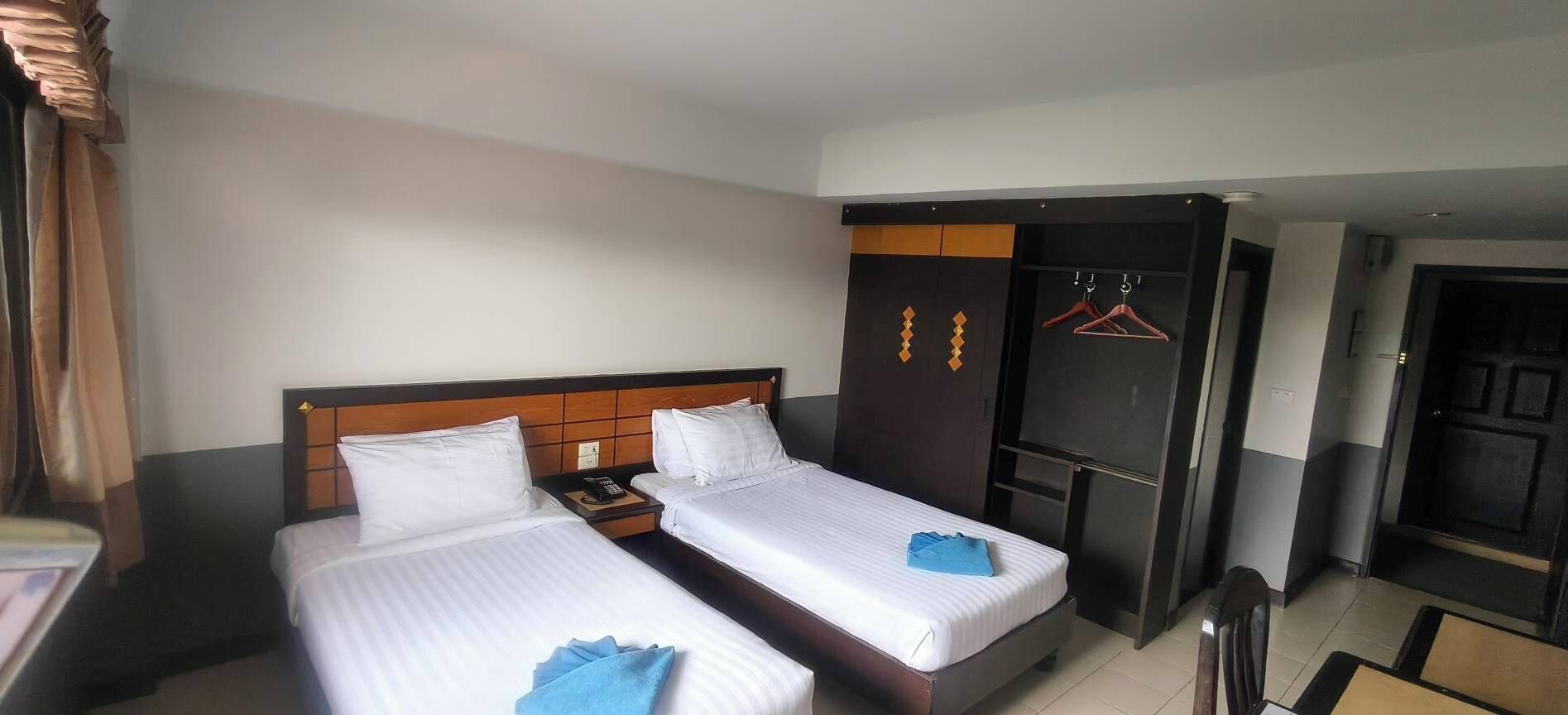 Une chambre d’hôtel avec deux lits, une armoire et un coin salon.