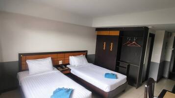 A hotel room with two beds, a wardrobe, and a seating area.