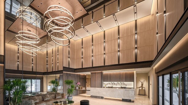 Un hall amplio con mostrador de recepción, zona de estar y grandes ventanales.