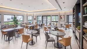 Un comedor moderno con mesas y sillas redondas, ventanas amplias y vista a la ciudad.