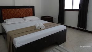 Ein Hotelzimmer mit einem Bett, einem Nachttisch und einem Fenster mit Vorhängen.