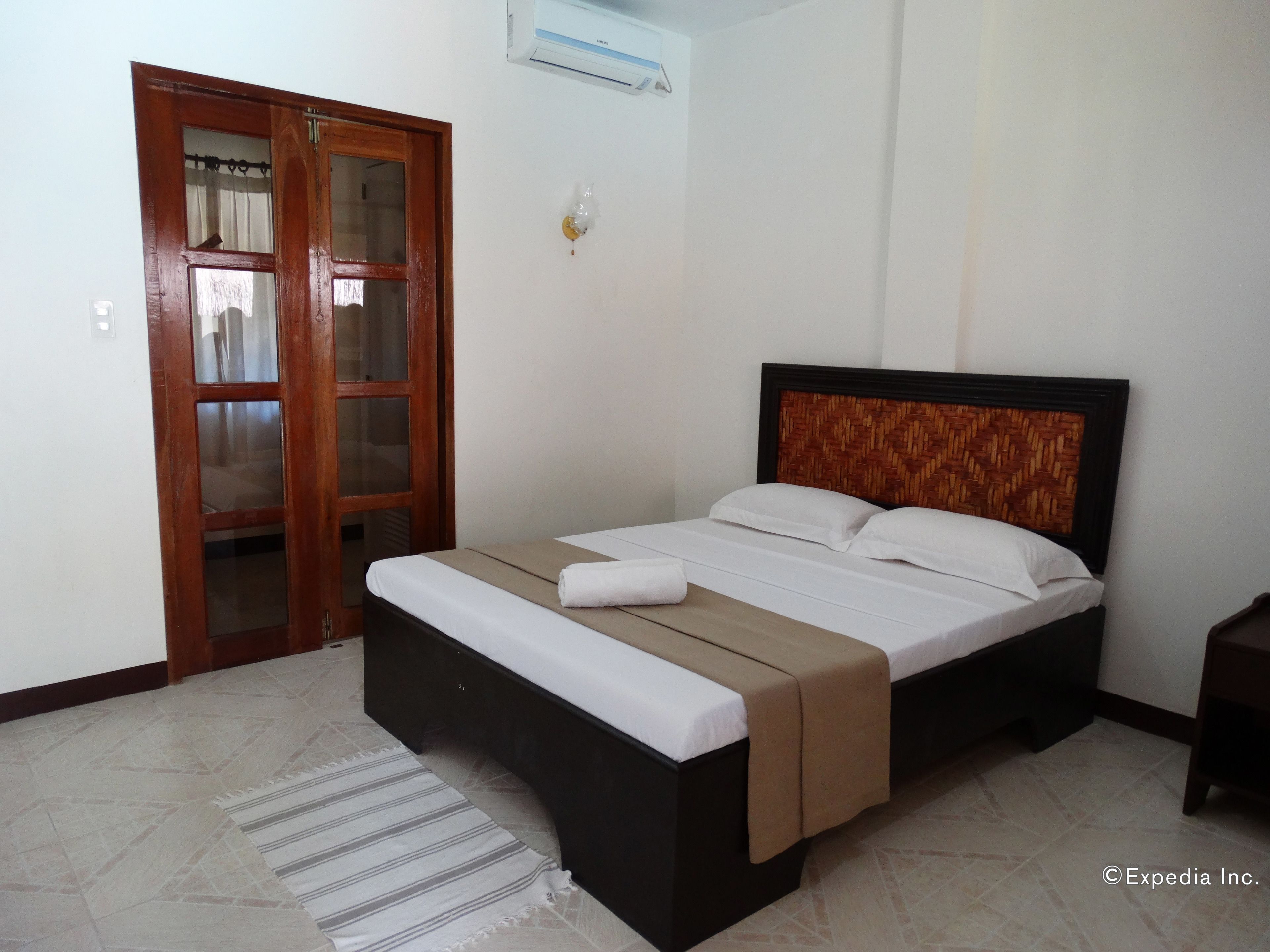 A bedroom with a bed, a wooden door, and a tiled floor.