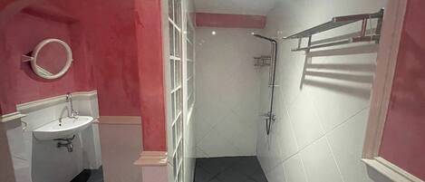 A bathroom with a sink, mirror, shower, and tiled floor.