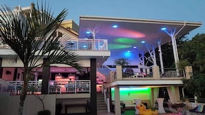 Una casa moderna con piscina, balcón y llamativas luces de techo de colores.