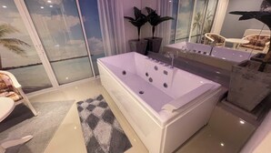 Un baño moderno con una bañera grande, una mesita con sillas y vistas al exterior a través de una puerta corrediza.