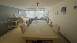 Un comedor moderno con una mesa de vidrio, sillas de cuero y una lámpara colgante.
