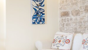 A white sofa with decorative pillows, a white ottoman, and a wall-mounted abstract painting. - Bella Bari rooms (Bari)