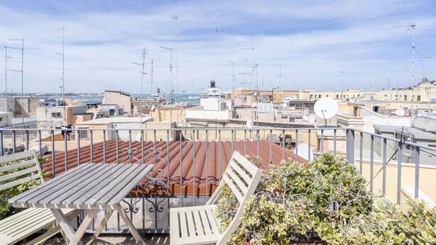A rooftop terrace with a view of the city, featuring a table and chairs, and a potted plant. - Bella Bari rooms (Bari)