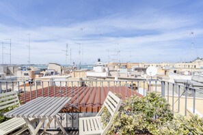 A rooftop terrace with a view of the city, featuring a table and chairs, and a potted plant. - Bella Bari rooms (Bari)