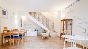 A spacious living area with a dining set, a sofa, and a staircase leading to an upper level. - Bella Bari rooms (Bari)